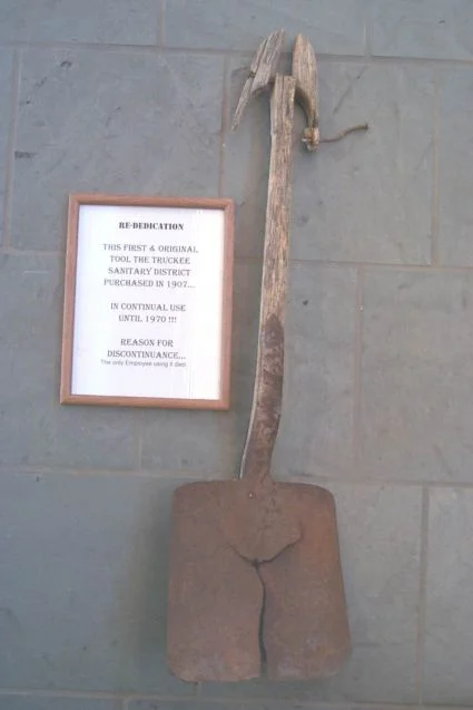 antique shovel with plaque next to it indicating it was the first shovel purchased by TSD in 1960
